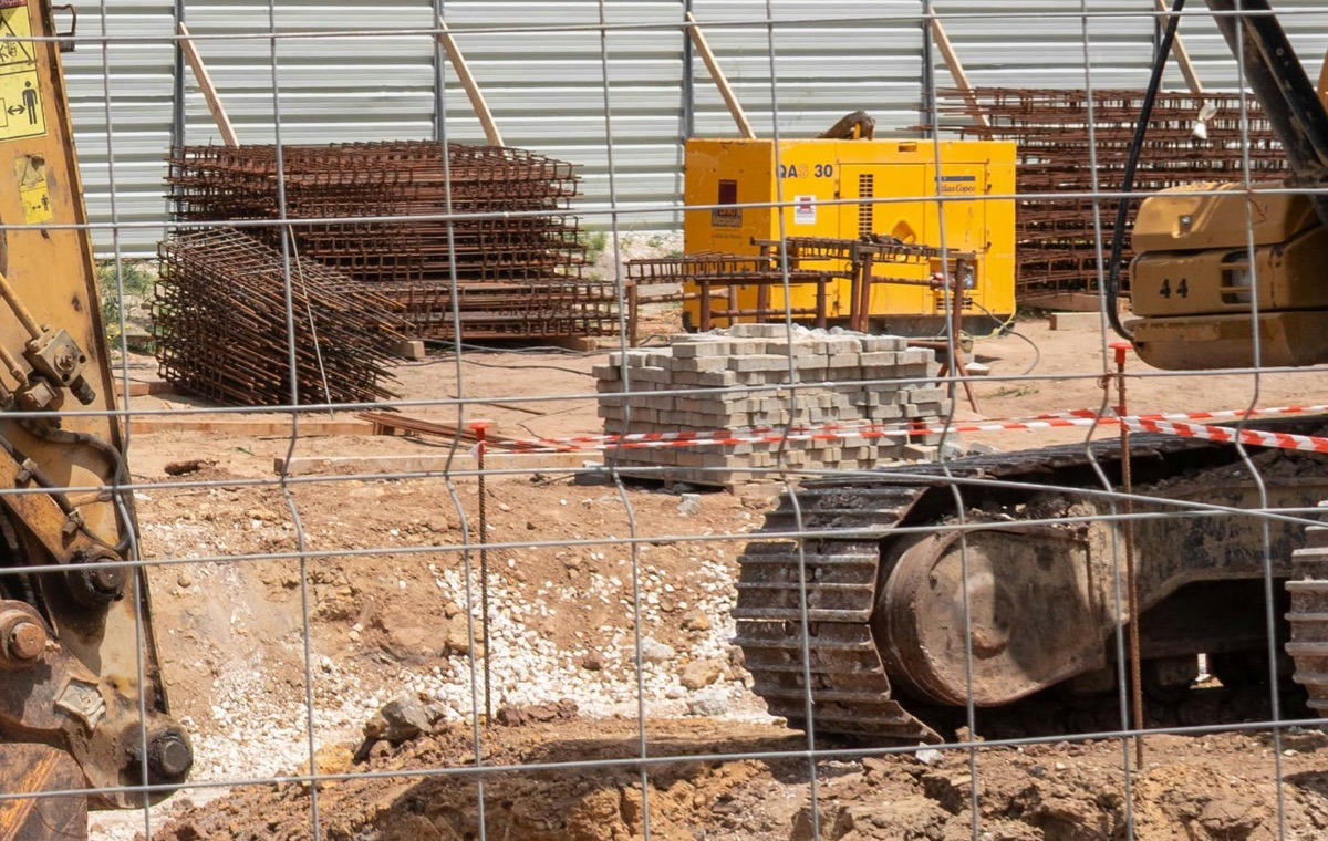 Stacks of rebar mesh, pallets of stone pavers and gravel on a construction site
